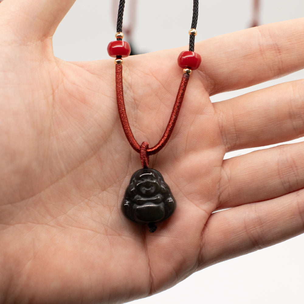Hand holding a red cord with a black pendant