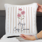 White pillow with pink flowers and 'Amy's Cosy Corner' text held by a person.