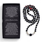 Black beaded necklace with red accents next to a black box with text on a white background