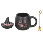 Black mug with 'Good Witch' text, small witch hat, and gold spoon on a white background
