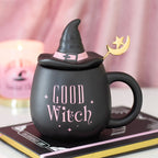 Black mug with 'Good Witch' text  in pink and witch hat on top, on a pink background