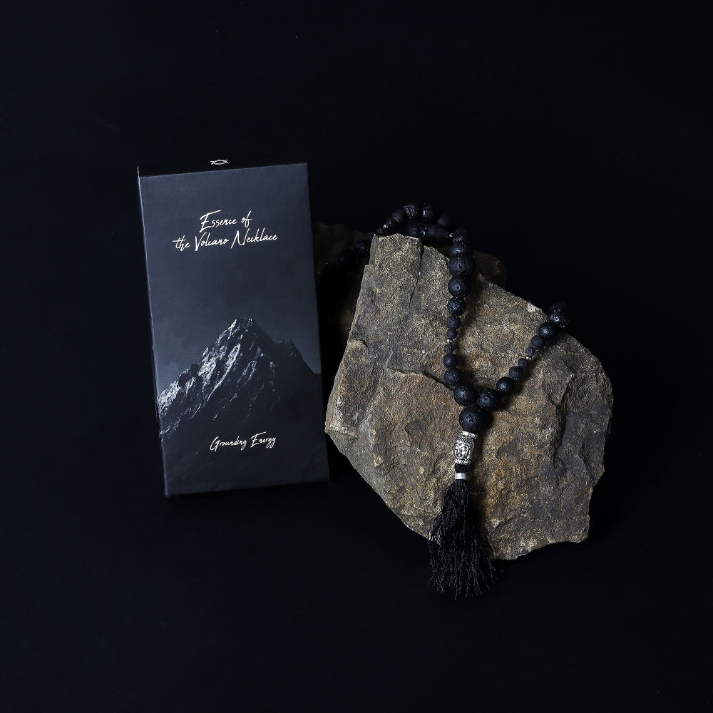 Black beaded necklace with tassel on a rock next to a mountain-themed card on a black background