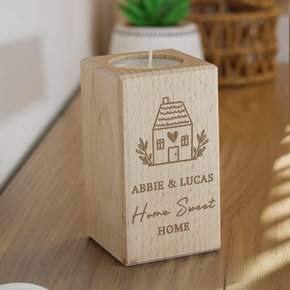 Wooden candle holder with engraved design and text on a wooden surface.