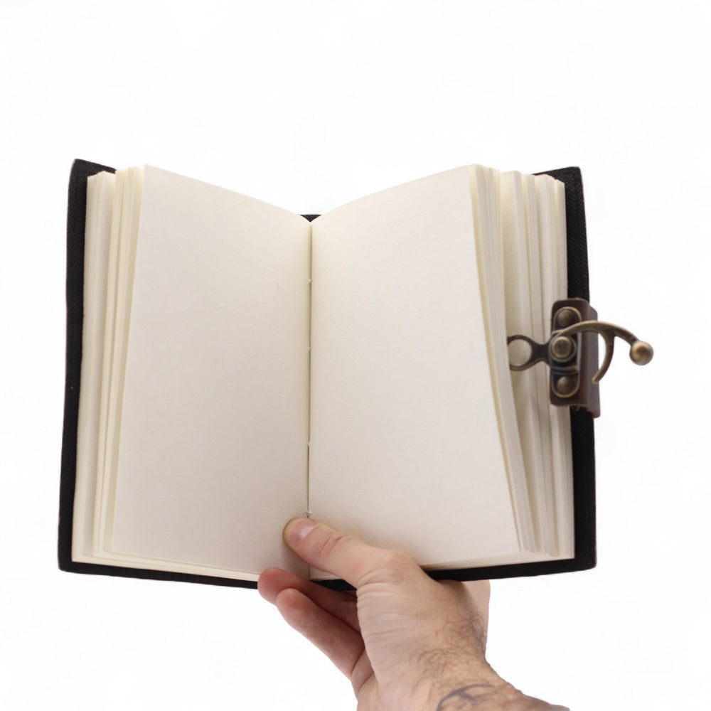 Hand holding an open notebook with a black leather cover on a white background