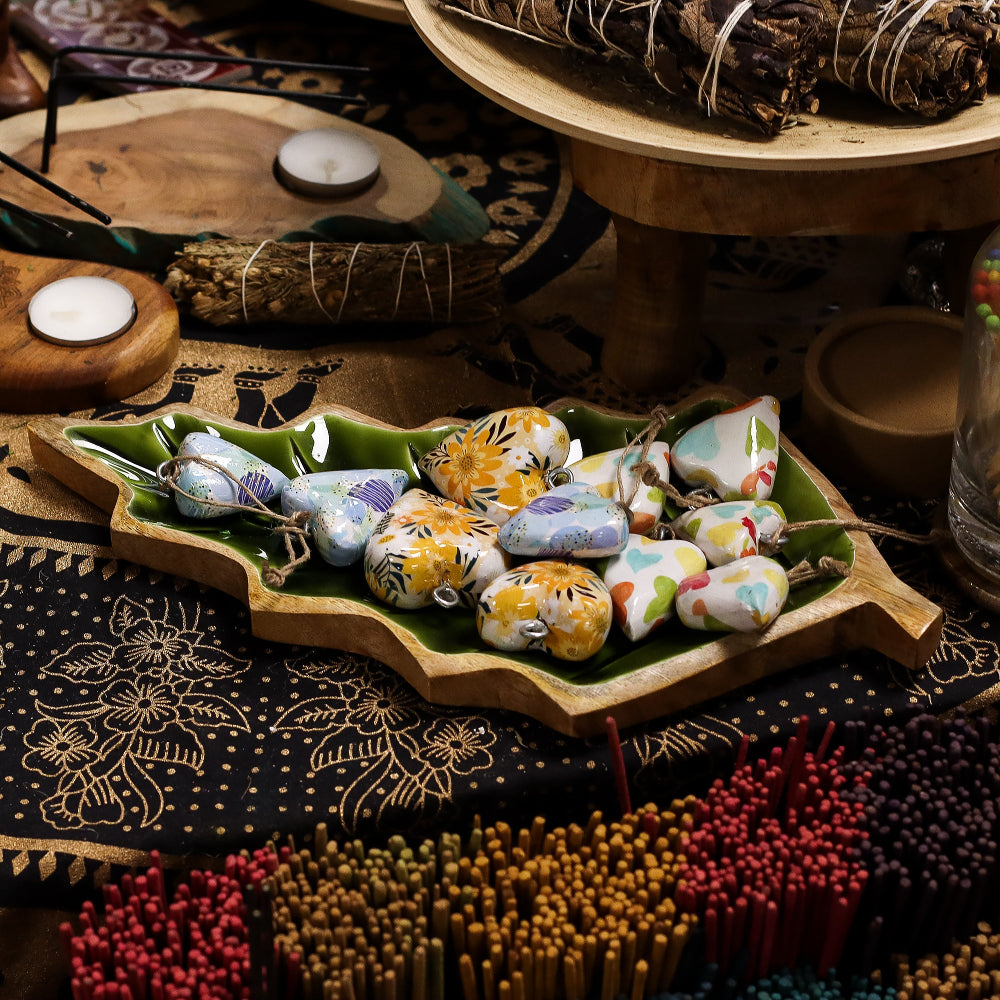 Colorful stones on a wooden tray with candles and herbs on a patterned surface