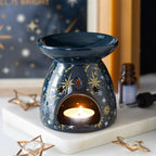 Navy blue wax warmer with a lit candle on a marble surface, surrounded by decorative items.