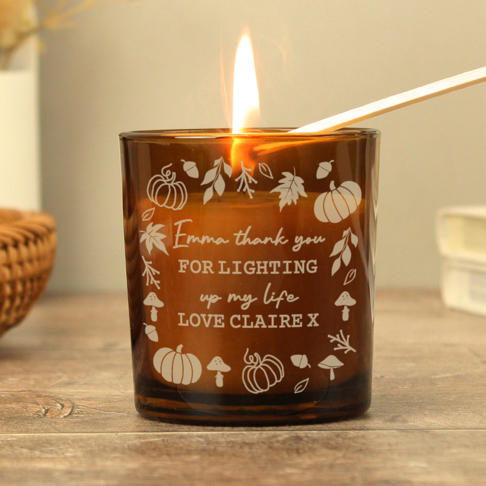 Brown candle with engraved text and illustrations on a wooden surface