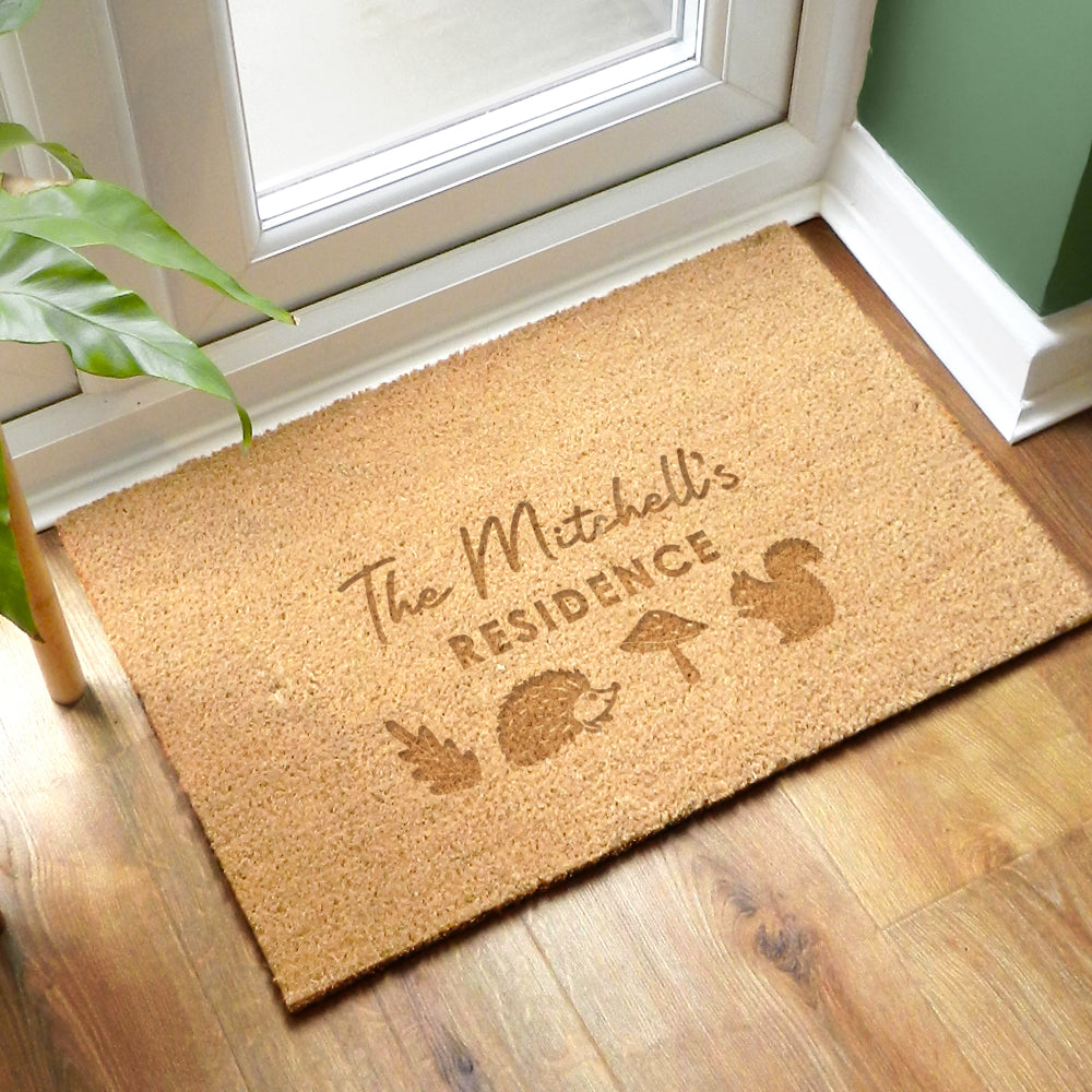 Doormat with 'The Mitchell's Residence' text and animal illustrations on a wooden floor.