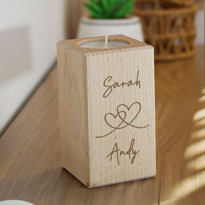 Wooden candle holder with engraved names 'Sarah' and 'Andy' on a wooden surface.