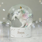 Unicorn figurine inside a snow globe with 'Freya' on a stand against a blurred background