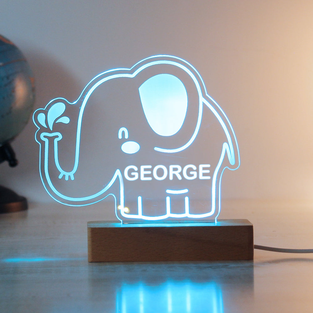 Neon light shaped like an elephant with 'GEORGE' on a wooden base.