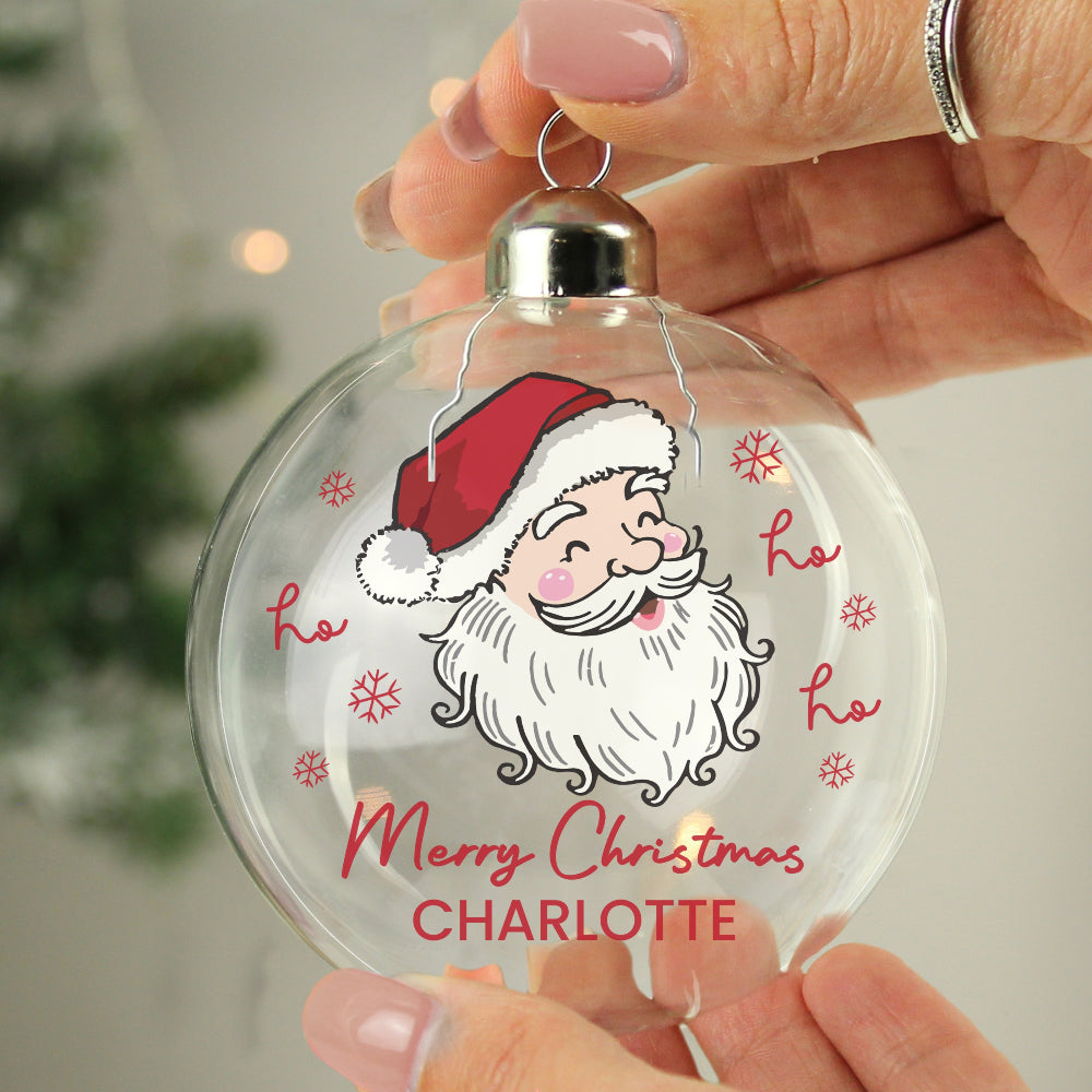 Clear Christmas ornament with Santa Claus design and 'Merry Christmas CHARLOTTE' text, held by a hand.