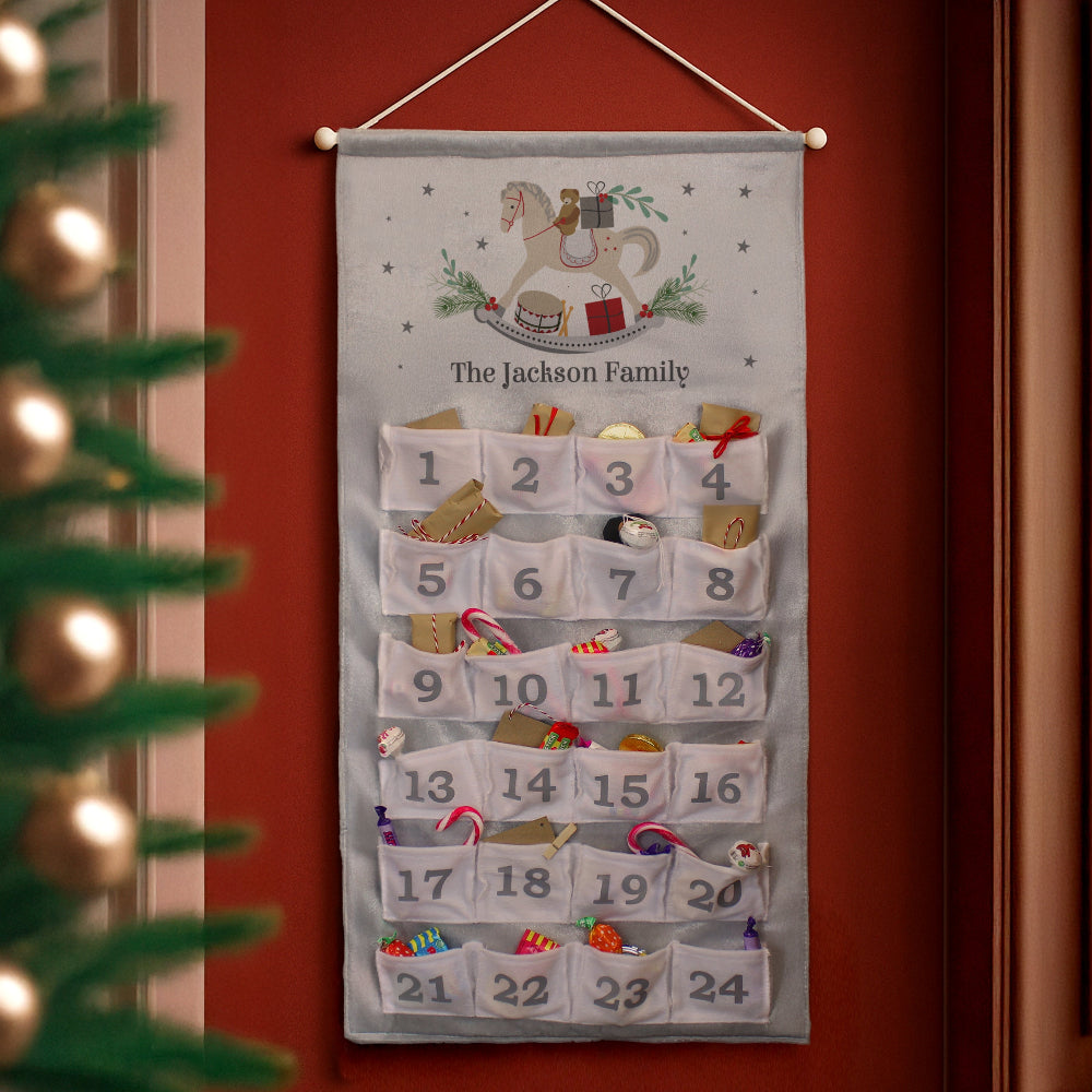 Advent calendar with festive design on a red wall next to a Christmas tree.