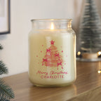 Candle in a glass jar with a Christmas tree design and 'Merry Christmas Charlotte' text, placed on a wooden surface.