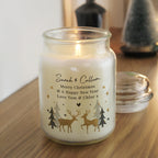 Candle in a glass jar with Christmas design and personalized text on a wooden surface.
