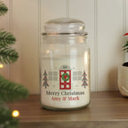 Personalized Christmas candle jar with decorative label on a wooden surface.