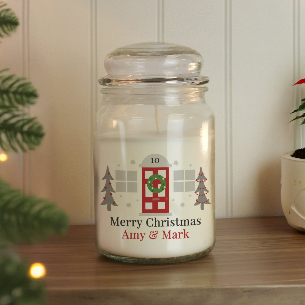 Personalized Christmas candle jar with decorative label on a wooden surface.