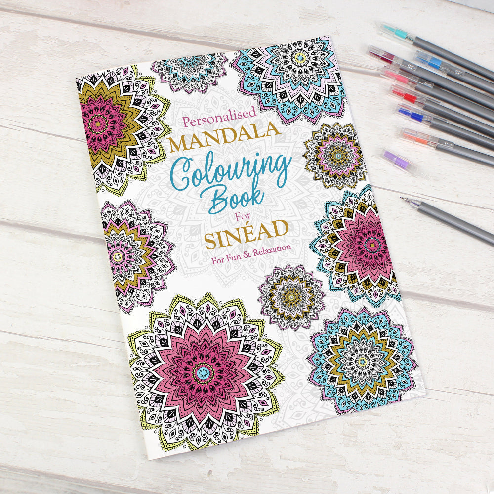 Personalized mandala coloring book with colored pencils on a wooden surface