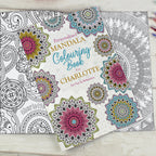 Personalized mandala coloring book with colorful designs on a wooden surface