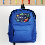 Blue backpack with space-themed design and 'Nathan' text, hanging on a wooden rack.