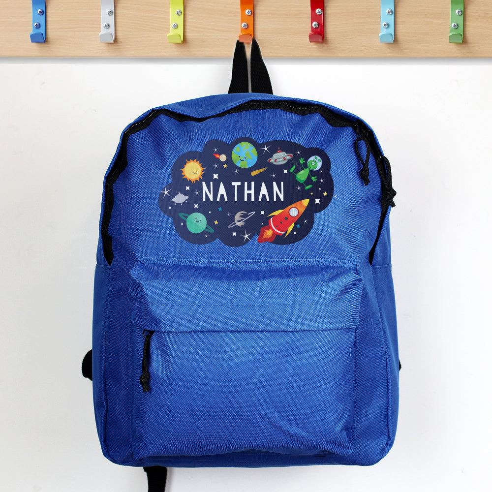 Blue backpack with space-themed design and 'Nathan' text, hanging on a wooden rack.