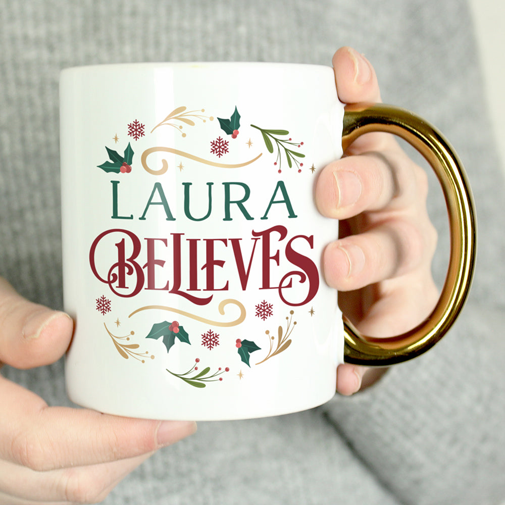 Mug with 'Laura Believes' text and decorative elements held by a person.