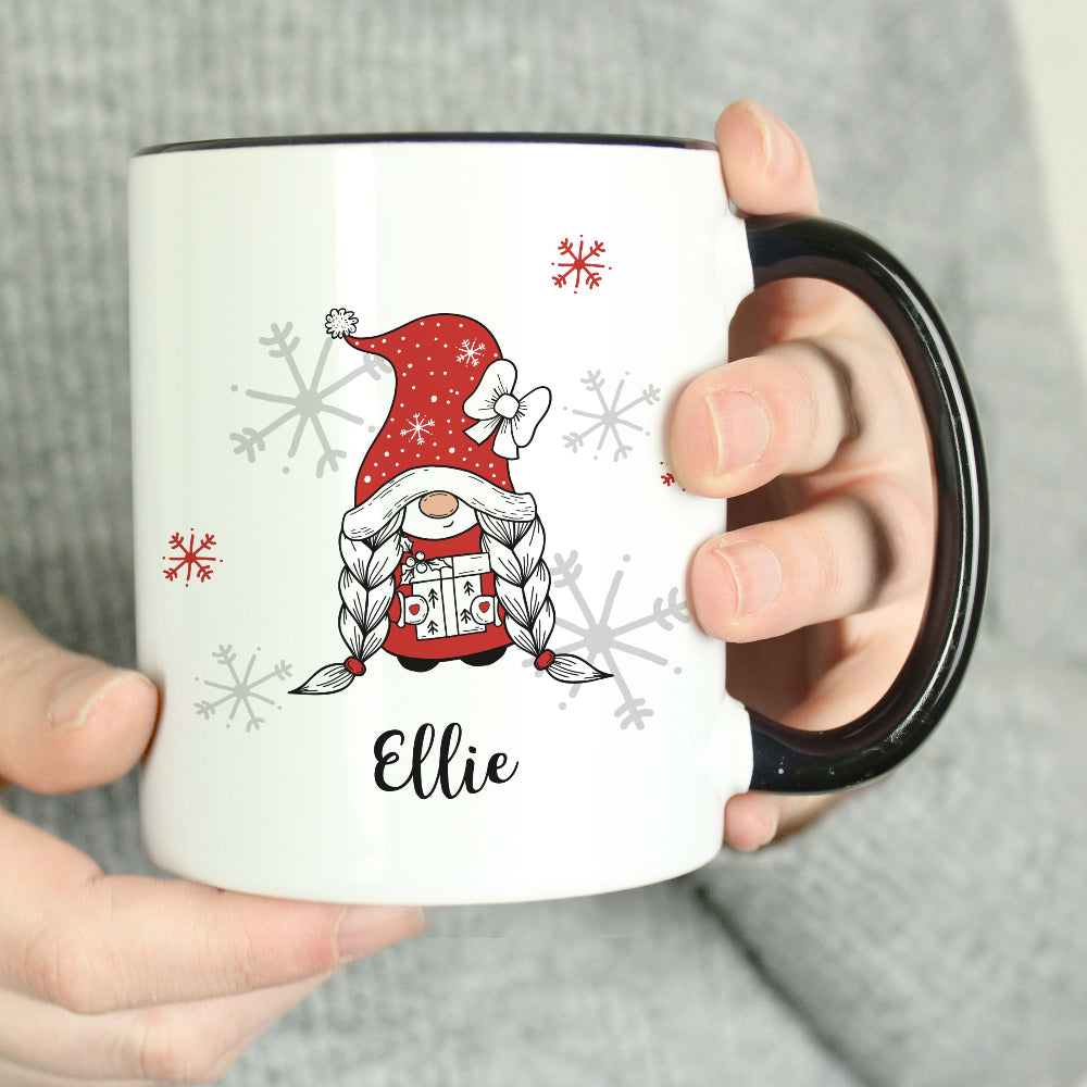 White mug with a Christmas-themed design featuring a gnome and snowflakes, held by a person.