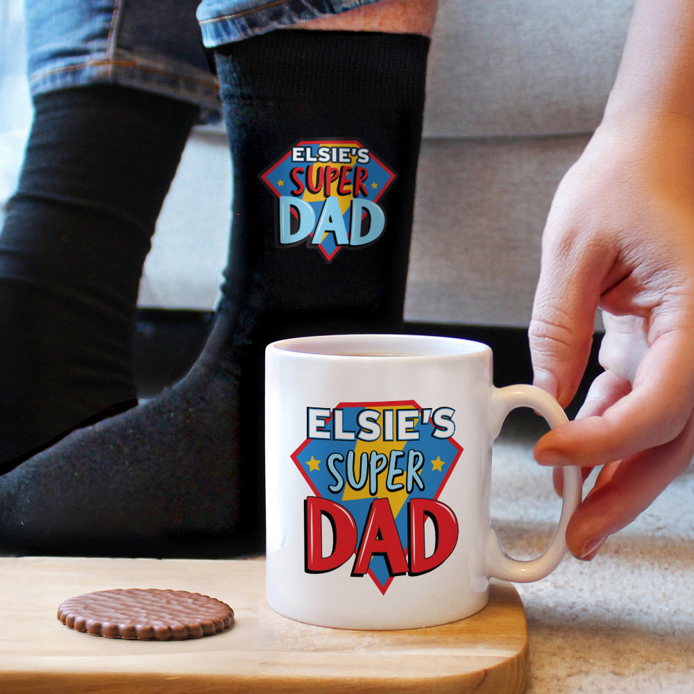 Mug with 'Elsie's Super Dad' design held by a hand on a wooden coaster.