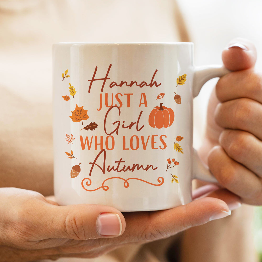 White mug with autumn-themed text and design held by a person
