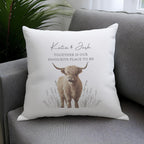 Decorative pillow with a highland cow illustration and text on a gray couch.