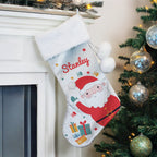 Christmas stocking with 'Stanley' on a fireplace mantle next to a decorated tree.