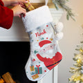 Christmas stocking with Santa design and 'Noah' text, being hung on a fireplace.