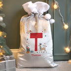 Personalized Christmas gift sack with festive design and letter 'T' on a decorated Christmas tree and presents background.