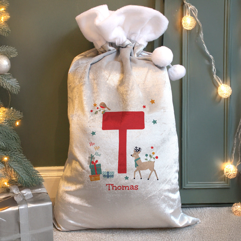 Personalized Christmas gift sack with festive design and letter 'T' on a decorated Christmas tree and presents background.