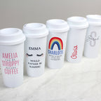 Set of personalized white tumblers with various designs and names on a light background