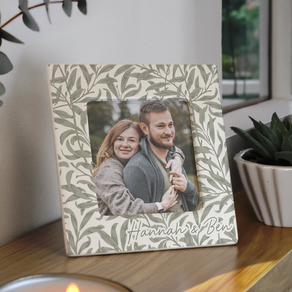 Decorative photo frame with a floral pattern and a couple's photo inside, placed on a wooden surface.