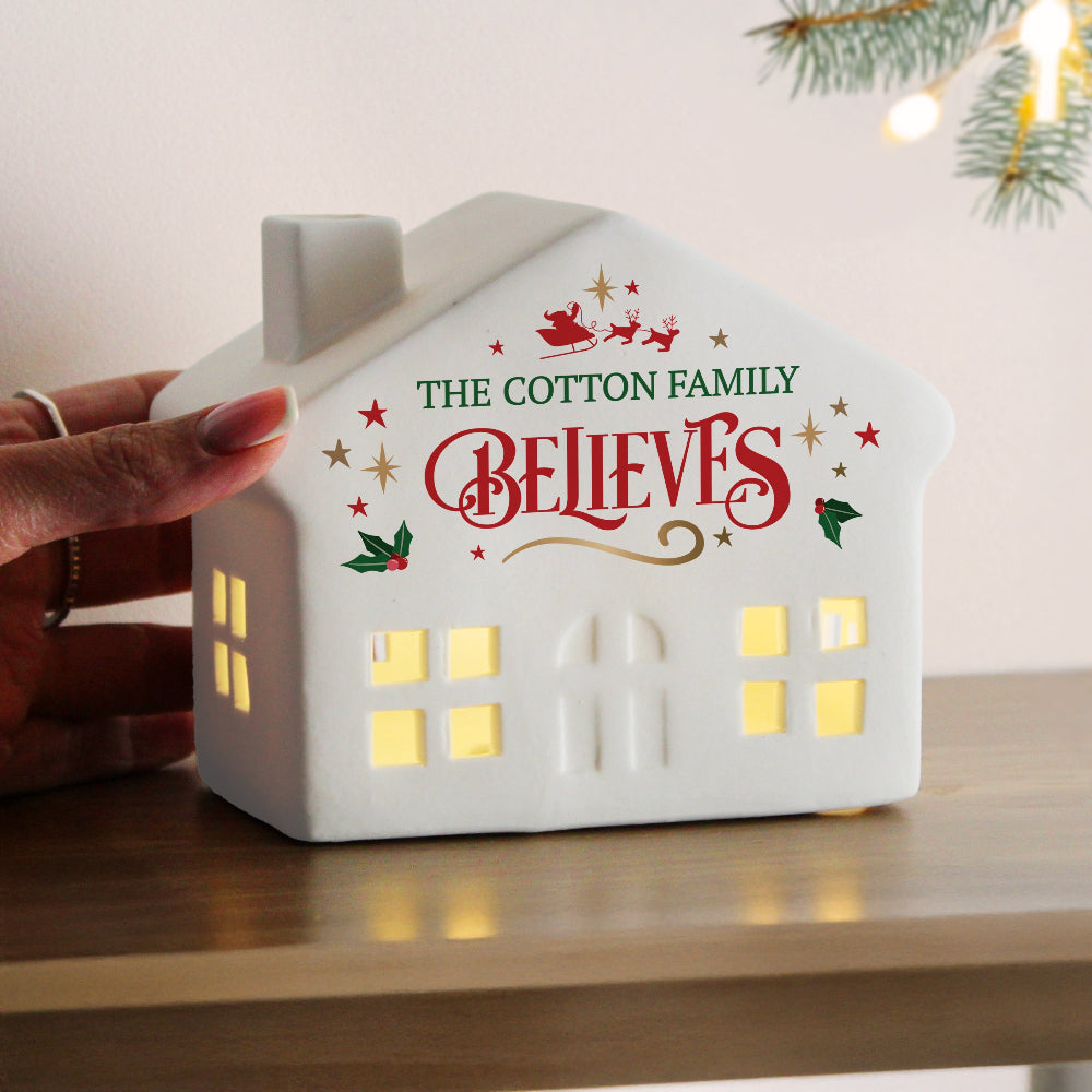 White house-shaped light with 'The Cotton Family Believes' text on a wooden surface.