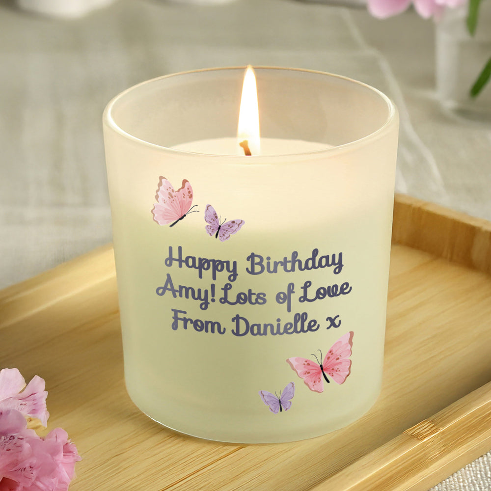 Candle with personalized message and butterfly designs on a wooden surface