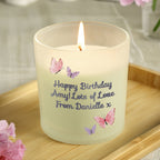 Candle with personalized message and butterfly designs on a wooden surface
