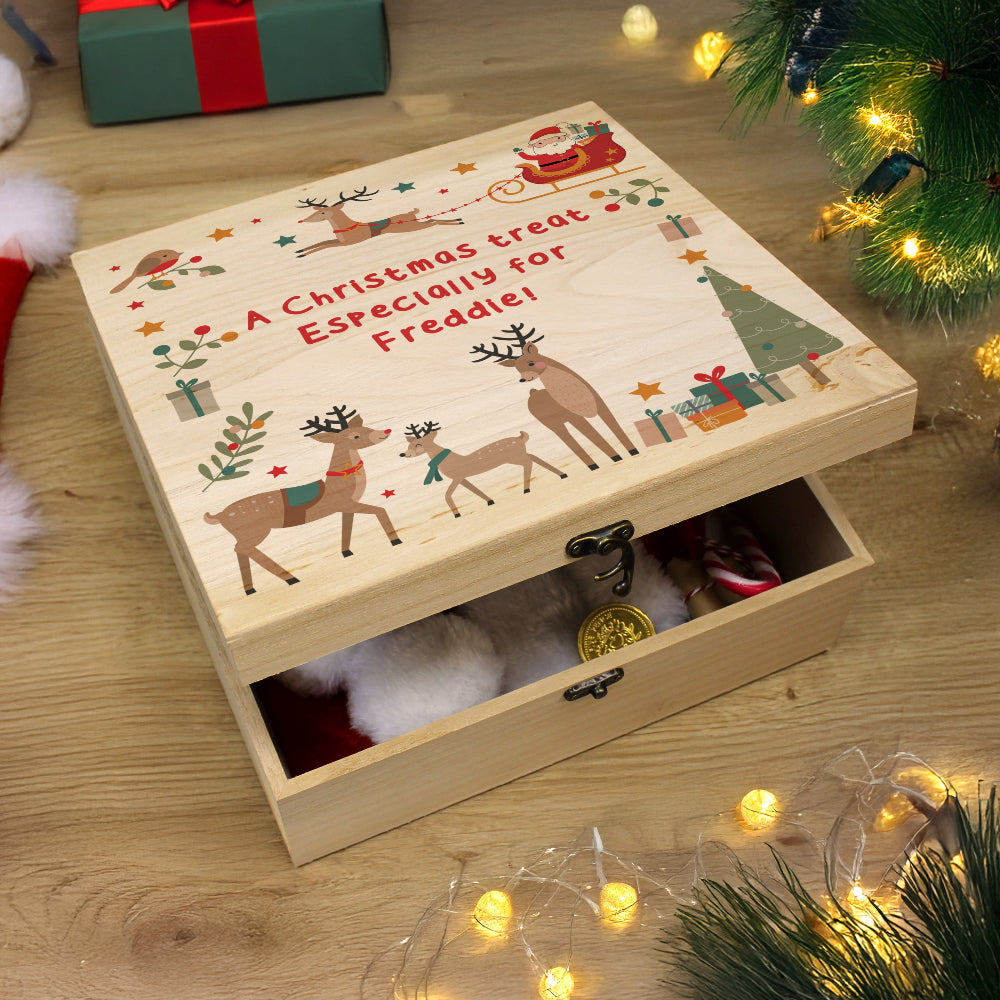 Wooden Christmas box with reindeer design and text on a wooden surface with festive decorations.