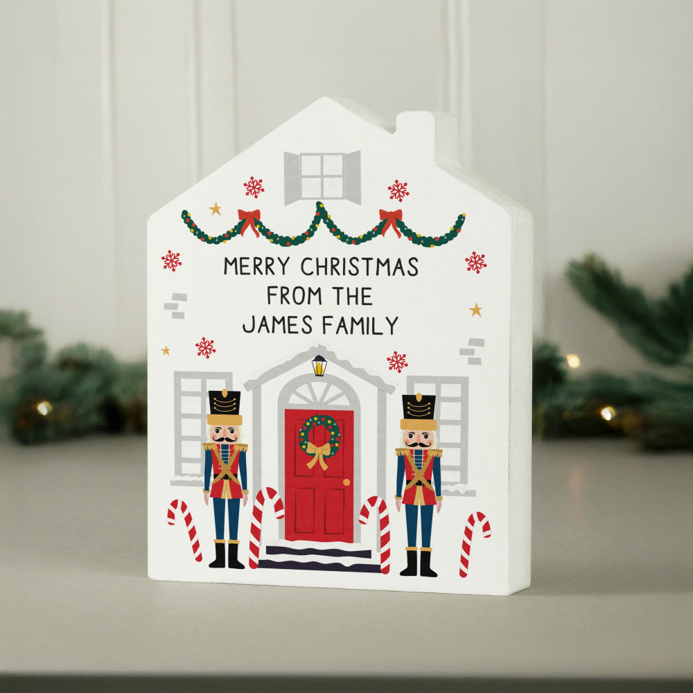 Decorative house-shaped Christmas card with Nutcrackers and candy canes on a neutral background.