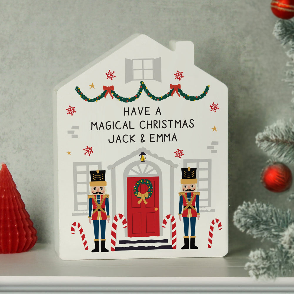 Decorative house-shaped sign with Christmas-themed design and personalized text on a gray background.