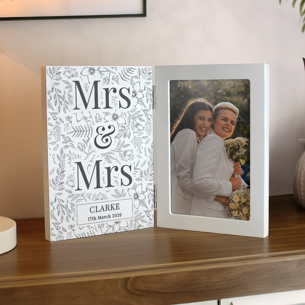 Personalized photo album with 'Mrs & Mrs' design on a wooden surface.
