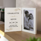 Personalized photo album with a couple's name and wedding date on a wooden surface.