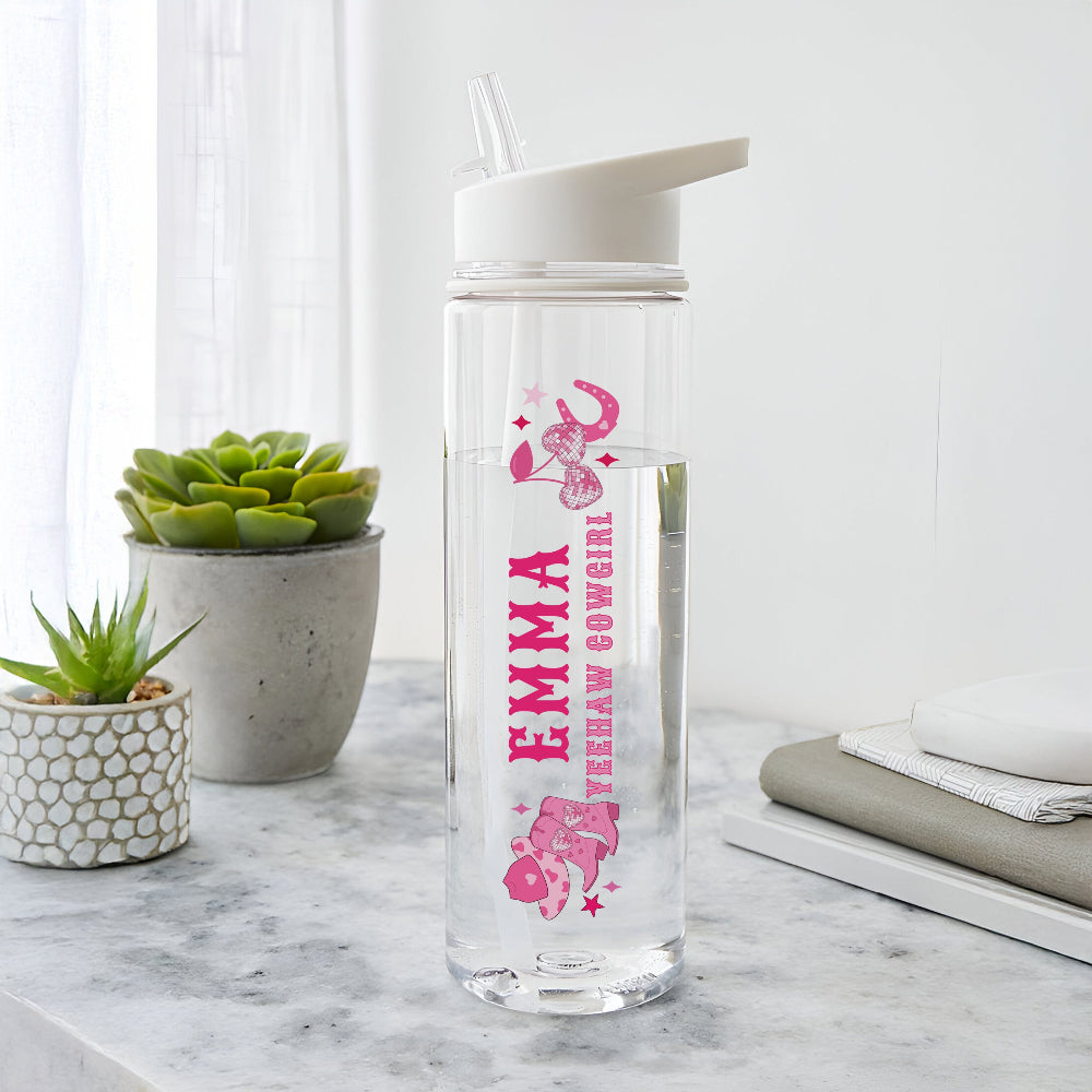 Clear water bottle with pink design and text on a marble surface with plants in the background