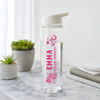 Clear water bottle with pink design and text on a marble surface with plants in the background