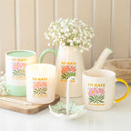 Decorative items including mugs, a pitcher, and a candle with 'No Rain No Flowers' text on a neutral background.