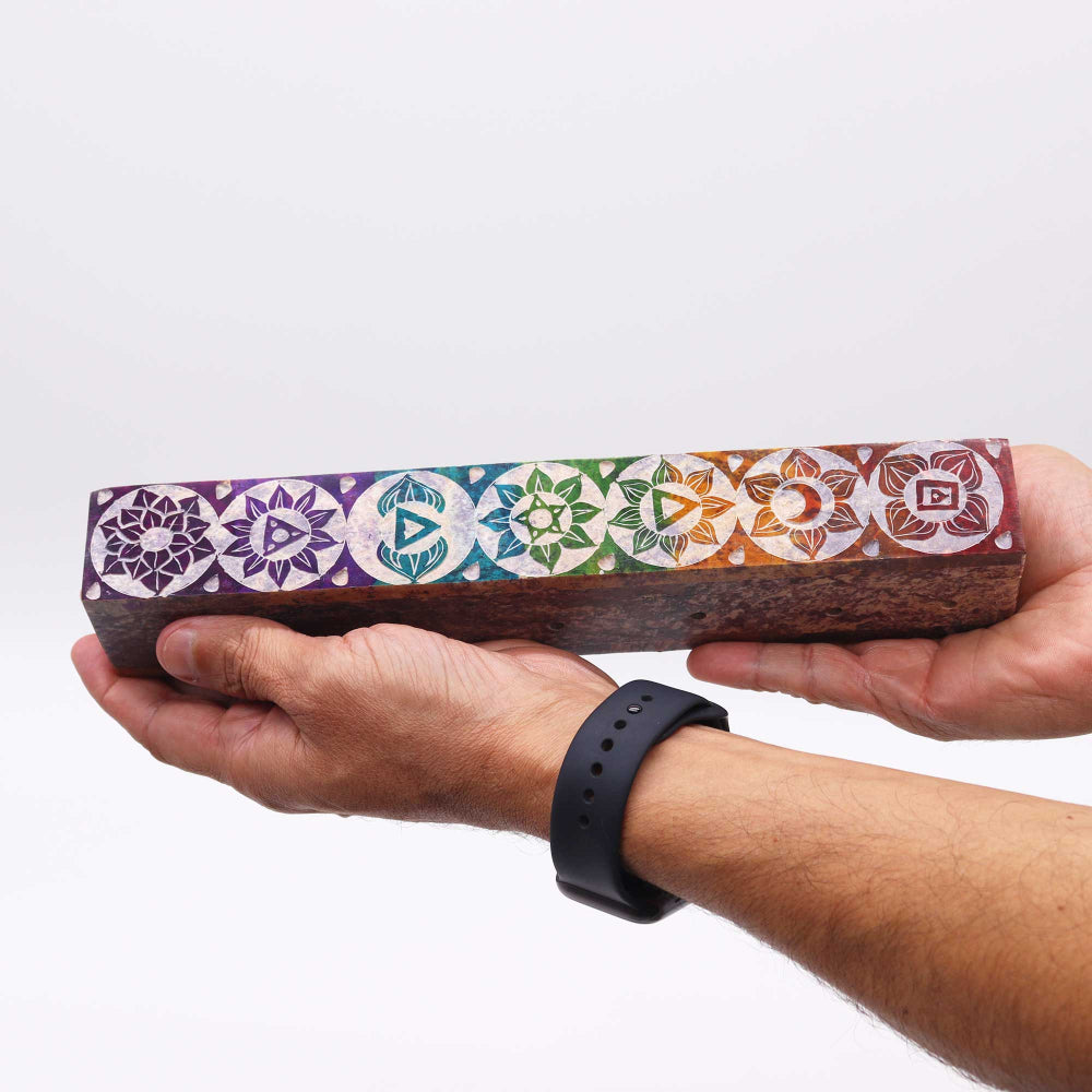 Person holding a wooden block with colorful geometric patterns on a white background