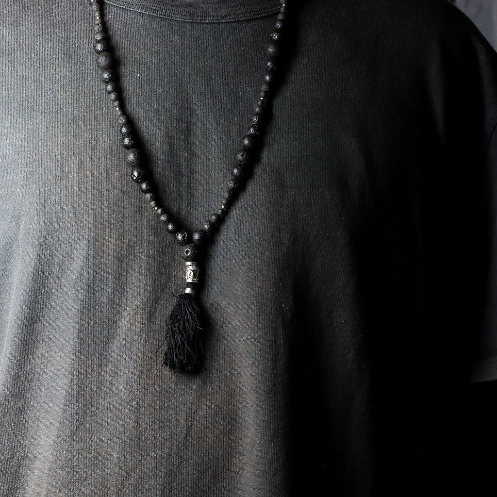Black beaded necklace with a tassel on a plain shirt