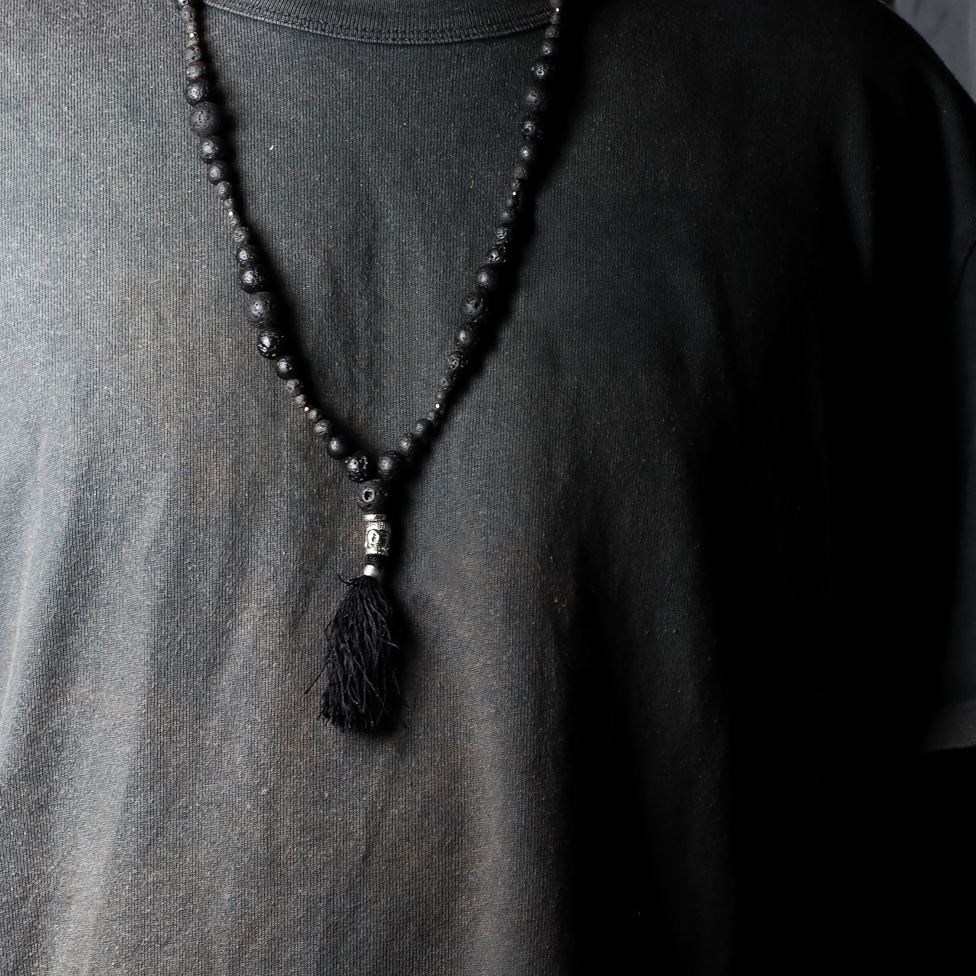 Black beaded necklace with a tassel on a plain shirt